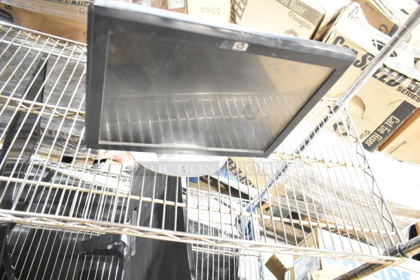 Three computer monitors on a metal shelf, featuring brands Dell and HP, in used condition with visible power and connectivity ports.