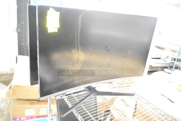 Four computer monitors, including a Samsung C32R500FHN and LG, on a metal rack. Visible wear and handwritten label attached.