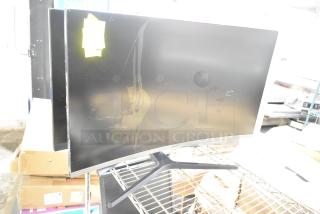 Four computer monitors, including a Samsung C32R500FHN and LG, on a metal rack. Visible wear and handwritten label attached.