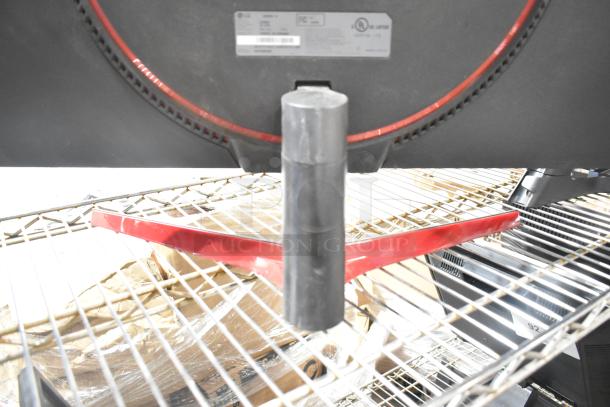 Four computer monitors including Samsung C32R500FHN and LG, displayed on metal shelving; condition appears used.