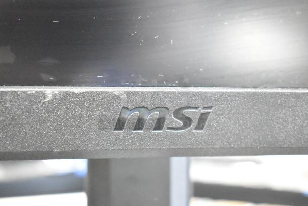 Close-up view of MSI logo on a computer monitor bezel, showing textured surface; subtle wear marks present.