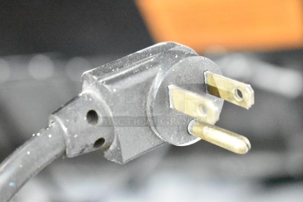 Power plug of Royal RVCDE-768-10 commercial vending machine, 115 volts, 1 phase, showing the metal prongs and black casing in detail.