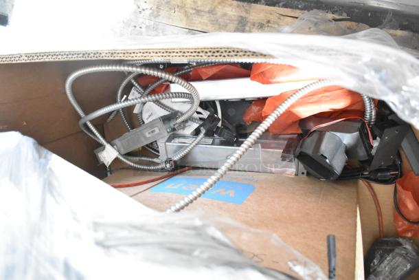 A box containing various electronics, including cables and monitors, with labels indicating Gen Speed and Paige brands. Good condition.