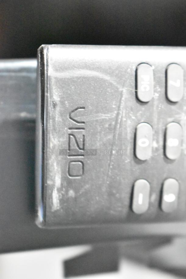 Samsung Luxfit LED Light Panel, close-up of Vizio remote, visible buttons, slight wear, black plastic.