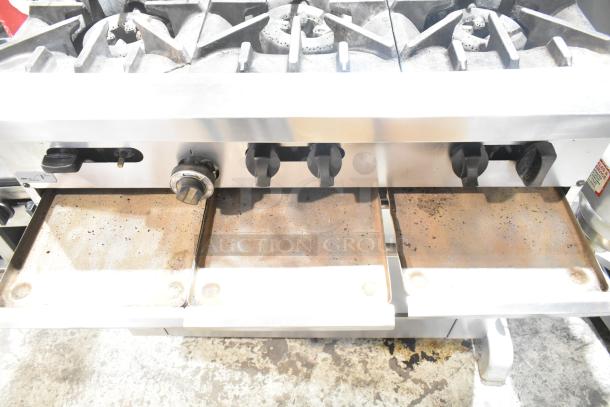 Garland SunFire stainless steel commercial 6-burner range, showing controls and burners. Built-in oven with overshelf and backsplash.