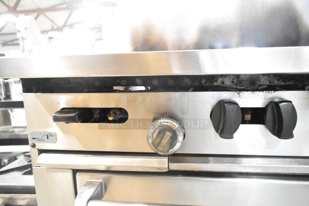 Garland SunFire stainless steel 6-burner range with oven, shelf, and backsplash, gas-powered, commercial use, visible controls.