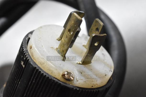 Close-up of a plug from Hobart H-600 commercial dough mixer. Features brass prongs and a white base.