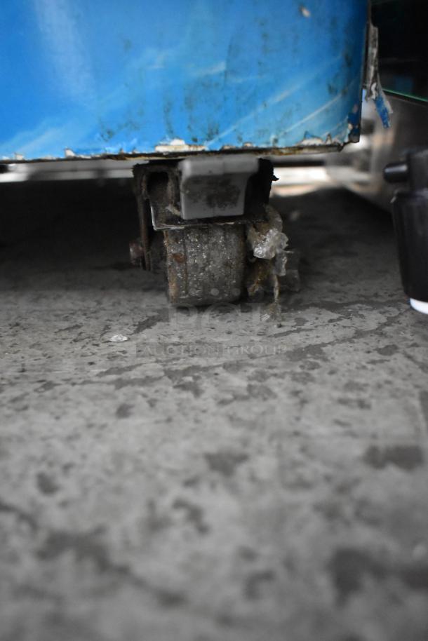 AHT Metal Commercial Freezer Merchandiser on worn caster, showing signs of use; 115 Volts, 1 Phase.