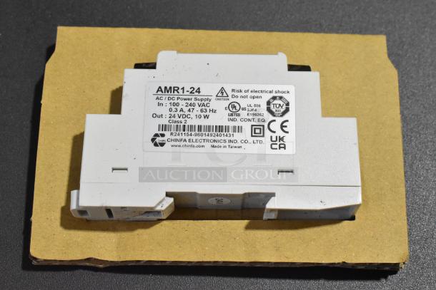 Brand new Chinfa AMR1-24 AC/DC power supply, 100-240VAC, 24VDC output, Class 2, made in Taiwan. Labels show certifications and warnings.