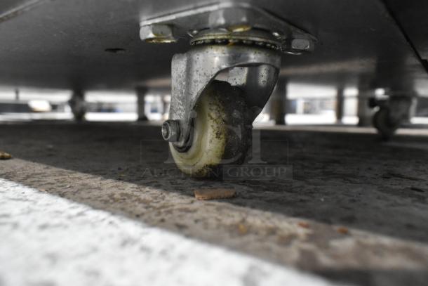 Close-up of a caster wheel on the Marchia MB48 stainless steel deli display case, showing moderate wear.