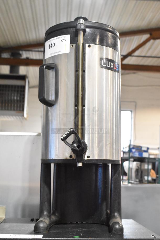 Fetco Luxus stainless steel beverage dispenser, commercial countertop, handle, spout, model marking visible, used condition.