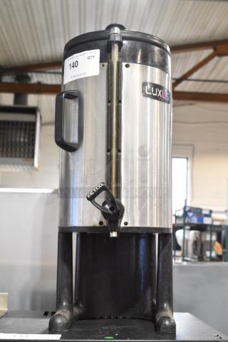 Fetco Luxus stainless steel beverage dispenser, commercial countertop, handle, spout, model marking visible, used condition.