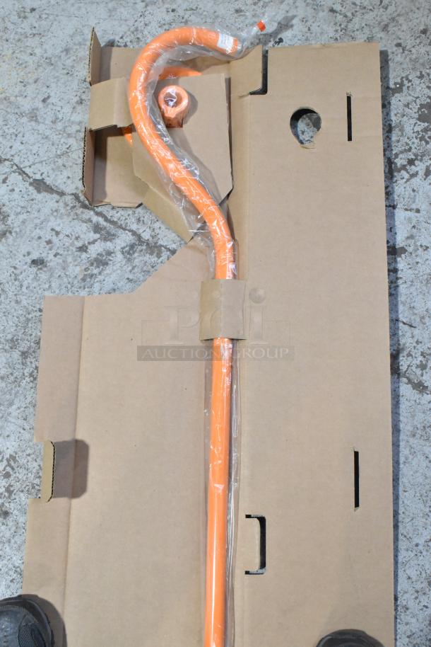 Brand new metal orange piece, curved shape, in original cardboard packaging, slight scratches visible, protective plastic wrap.