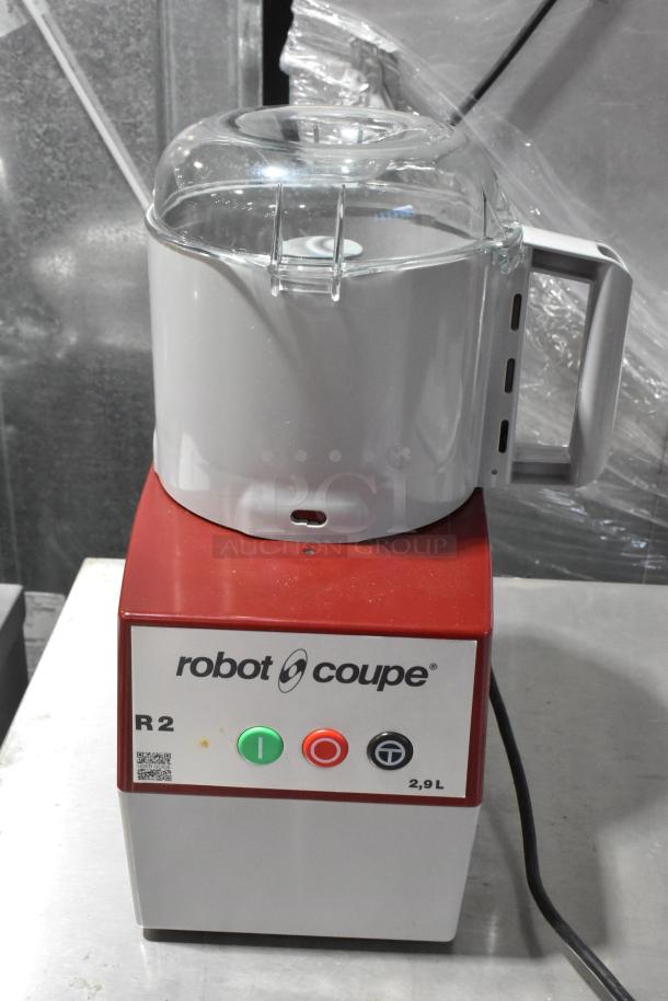 Robot Coupe R2N metal food processor with bowl, lid, continuous feed head, grater blade, and slicing blade.