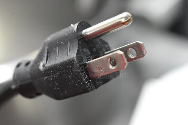 The image shows a close-up of a standard U.S. electrical plug, black, with visible prongs.