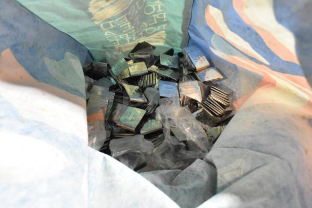 Lot of metal number signs and standing clipboard menu holders in a colorful bag. Various numbers visible on signs.