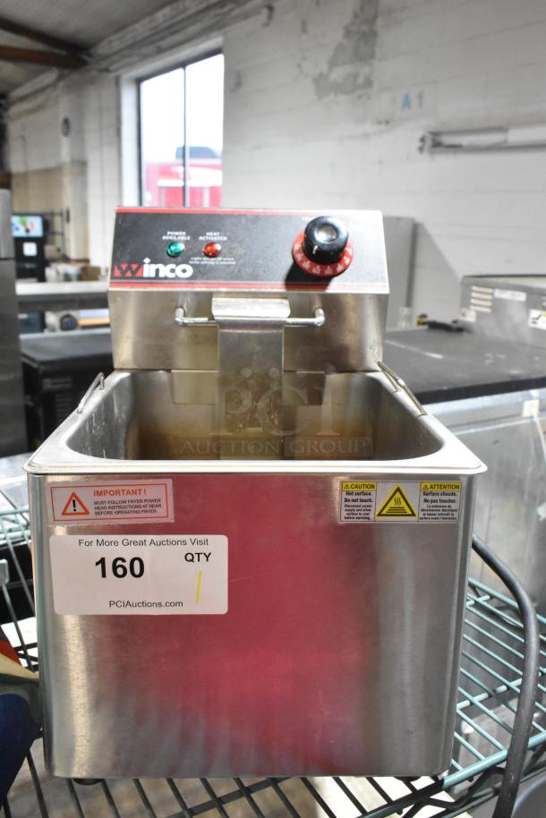 Winco stainless steel countertop electric deep fryer with metal basket, 115 volts, 1 phase; features caution labels and temperature dial.