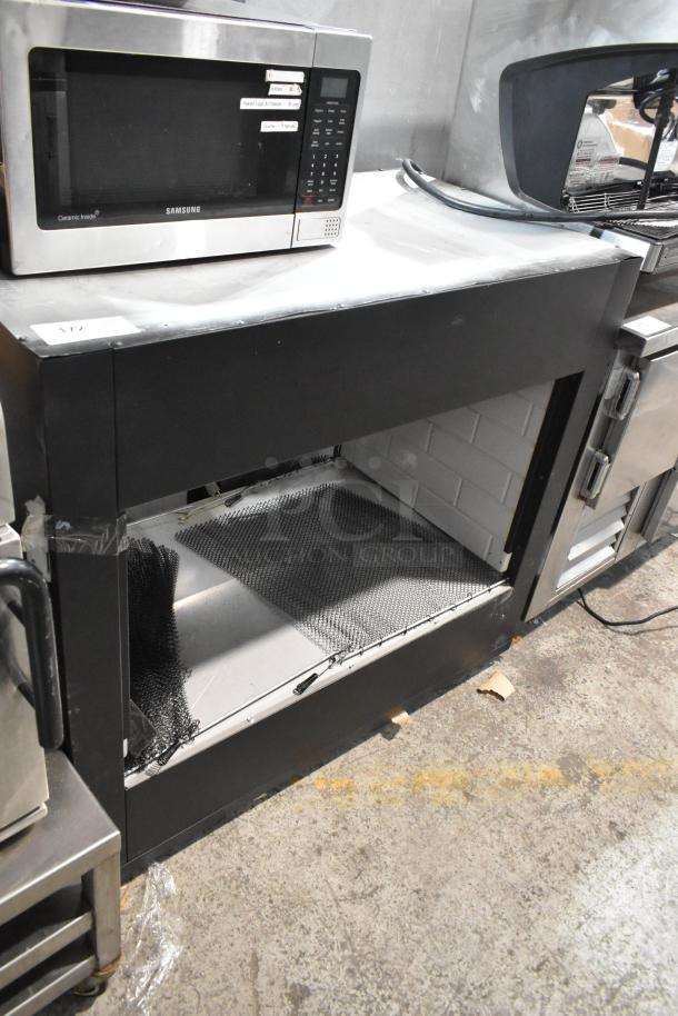 Steel table with under shelf, black exterior, and used condition. Includes storage space below. Visible ID tag 172 on top.