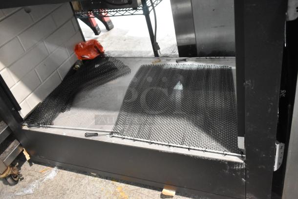 Industrial table with under shelf, metal frame, and mesh covers. Shows slight wear, suitable for storage or utility use.