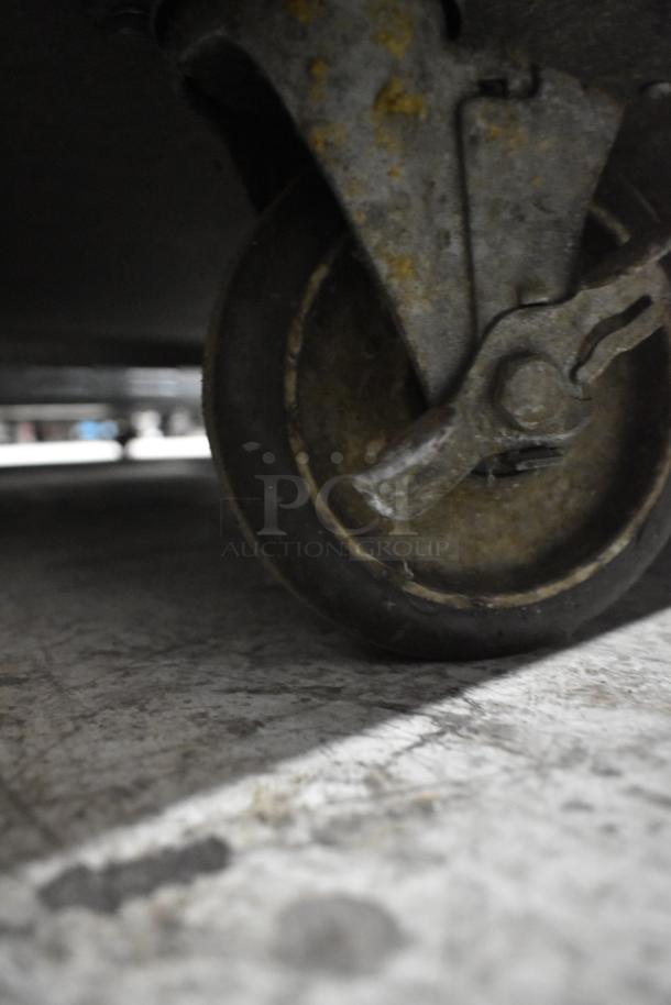 Close-up of a caster wheel on a CresCor H137UA12D Heated Holding Cabinet, showing metal and rubber materials.