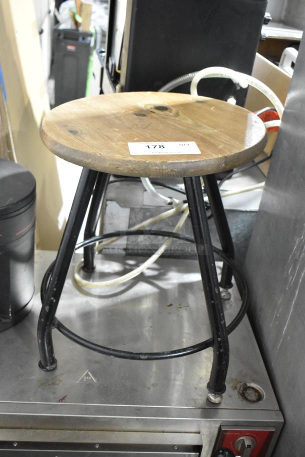 Wooden and black metal stool with round wooden seat, black metal legs. Visible tag labeled "178". Slight wear evident.