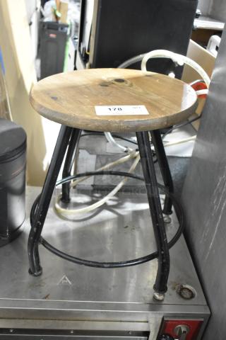 Wooden and black metal stool with round wooden seat, black metal legs. Visible tag labeled "178". Slight wear evident.