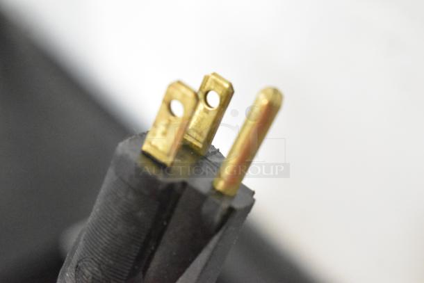 Close-up view of a three-prong plug, possibly part of a commercial merchandiser, highlighting electrical connectivity.