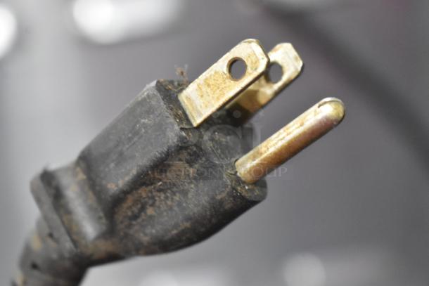 Close-up of a used electrical plug for a Hatco GRMW-3 Heated Merchandiser, showing wear on the prongs and casing.