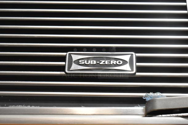 Sub-Zero logo on wood panel of 2-door reach-in cooler, 115V, 1-phase. Features built-in freezer; part of high-end refrigeration unit.