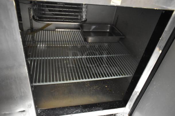 2020 Leader NLM60 Stainless Steel Prep Table interior showing wire shelving and a stainless steel pan, used condition.