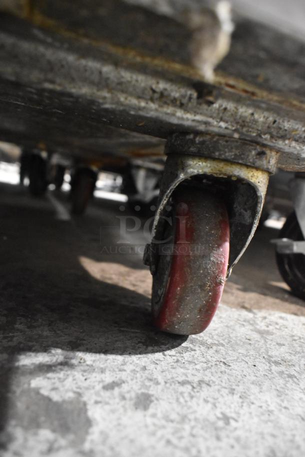 2020 Leader NLM60 stainless steel prep table caster, showing signs of wear, part of a commercial kitchen setup.