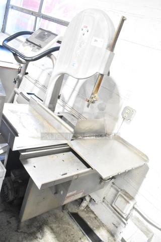 Metal commercial floor-style meat saw, robust frame, used condition. Includes safety markings and adjustable components. Ideal for heavy-duty use.