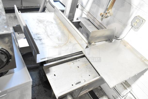 Metal commercial floor-style meat saw in used condition; features stainless steel build and adjustable cutting surface.