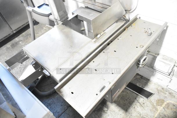 Metal commercial floor-style meat saw with stainless steel body. Features a sturdy cutting surface and robust construction. Used condition.