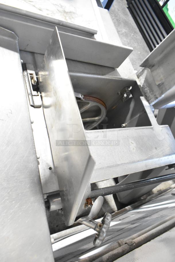 Metal commercial floor-style meat saw with stainless steel components, showing cutting area and adjustment knobs, in used condition.