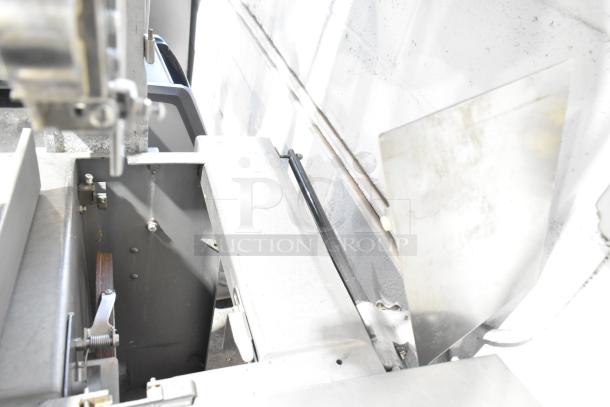 Metal commercial floor-style meat saw, robust design, in good condition. Visible metal components and mechanisms. Suitable for heavy-duty use.