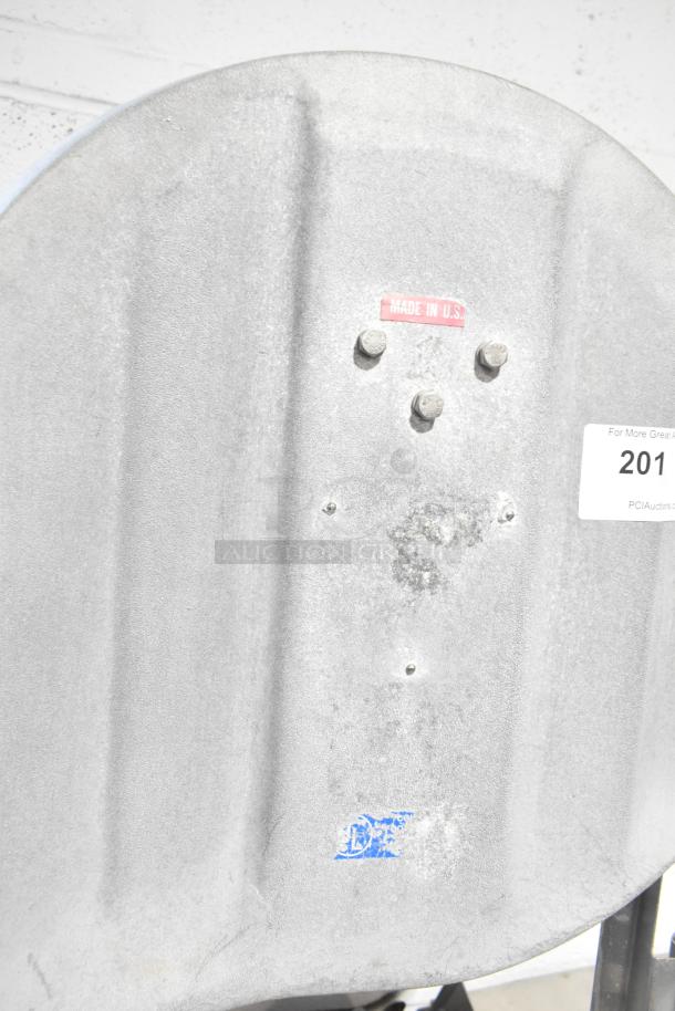 Metal commercial floor-style meat saw, marked "Made in U.S." on a metal surface with visible bolts, showing wear.