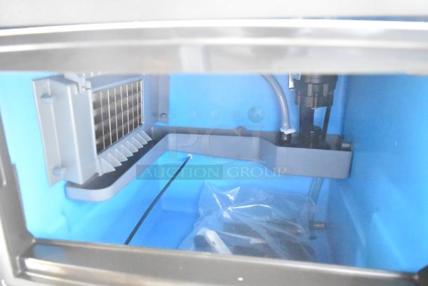 Manitowoc UDP-0065A undercounter ice machine interior, showing new, stainless steel bin and ice-making components.