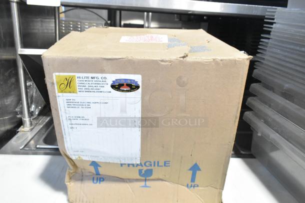 Cardboard box with Hi-Lite Mfg. Co. label, containing brand new scratch and dent orange fixture and hose. Fragile markings visible.