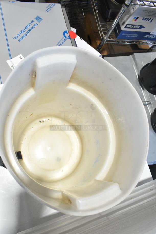 Various items including a white poly bin with visible dirt marks, placed on a shelf with boxes in a warehouse setting.