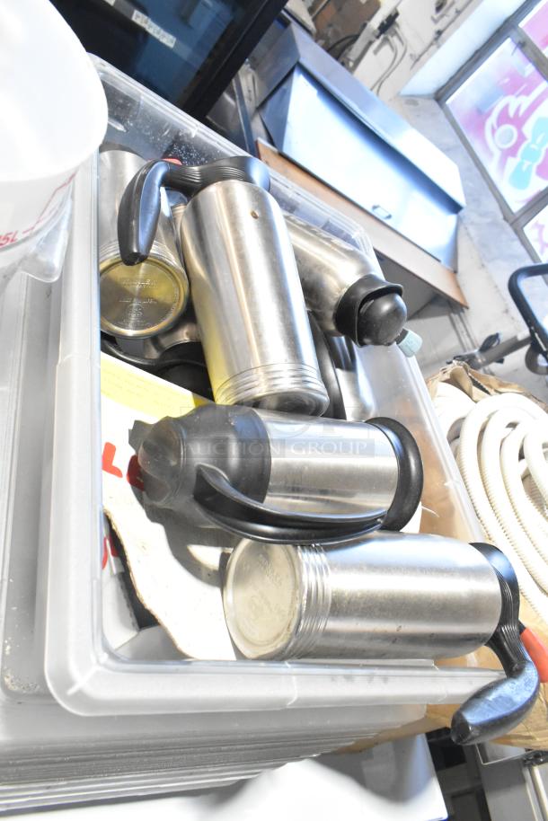 Lot of assorted items including stainless steel thermoses in a clear poly bin. Mixed condition, suitable for storage or resale.