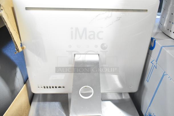 Apple iMac all-in-one computer, rear view showing ports and stand, white casing with visible wear marks.
