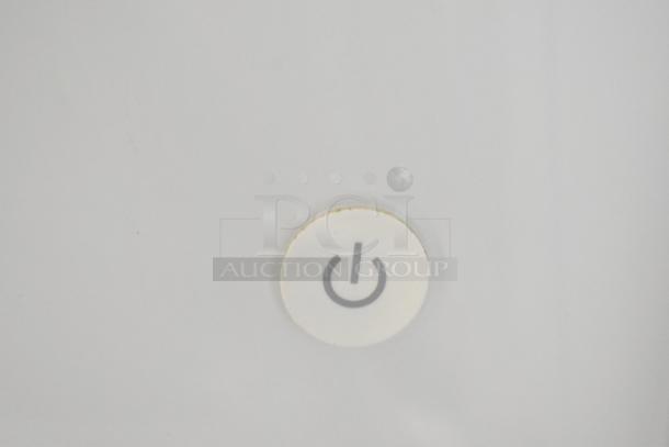 Power button on Apple iMac All In One Computer, indicating functionality, set against a smooth grey surface.