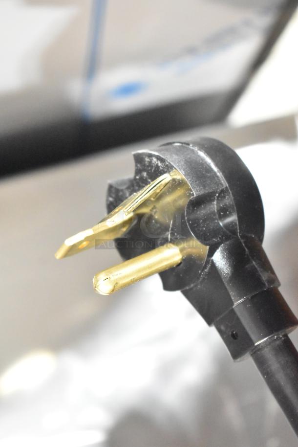 Plug of Amana RC30S2 stainless steel commercial microwave, 208/240 volts, showing prongs and black casing.