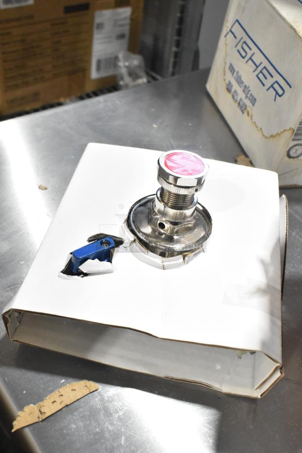 Pallet with various items: Fisher faucet handle, coupler, box labeled Fisher, metal items on a shiny surface.