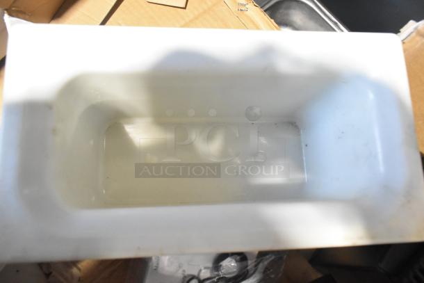 Pallet with various items including white rectangular tank, cardboard boxes, and metal objects. Mixed condition.