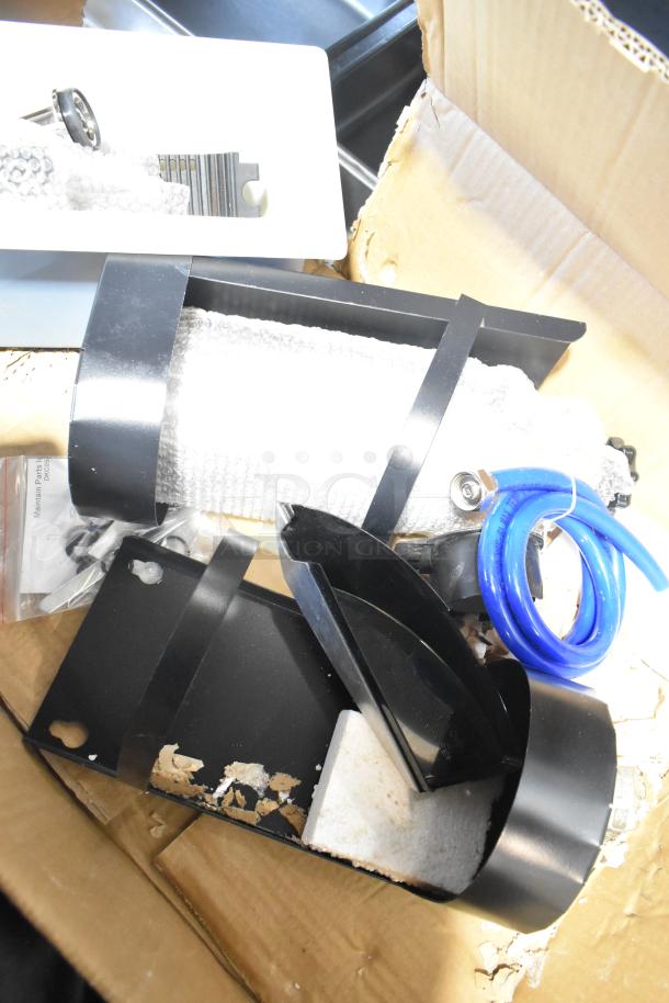 Pallet lot with various items including metal baskets, grease filters, blue hose, and hardware parts in a cardboard box.