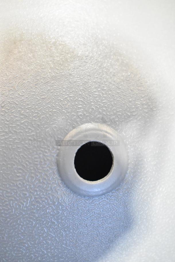 Close-up of textured metal surface with a central round opening, possibly part of an item from the mixed pallet lot.