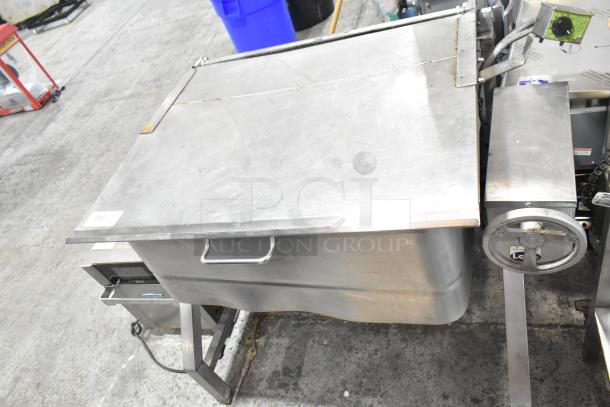 Stainless Steel Commercial Braising Pan with lid and manual tilt handle, industrial-grade, good condition, minor wear.