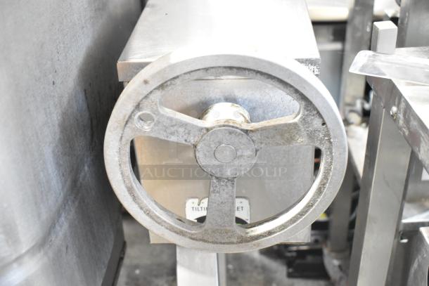 Stainless steel commercial braising pan with a tilting mechanism. Features robust construction and visible wear.